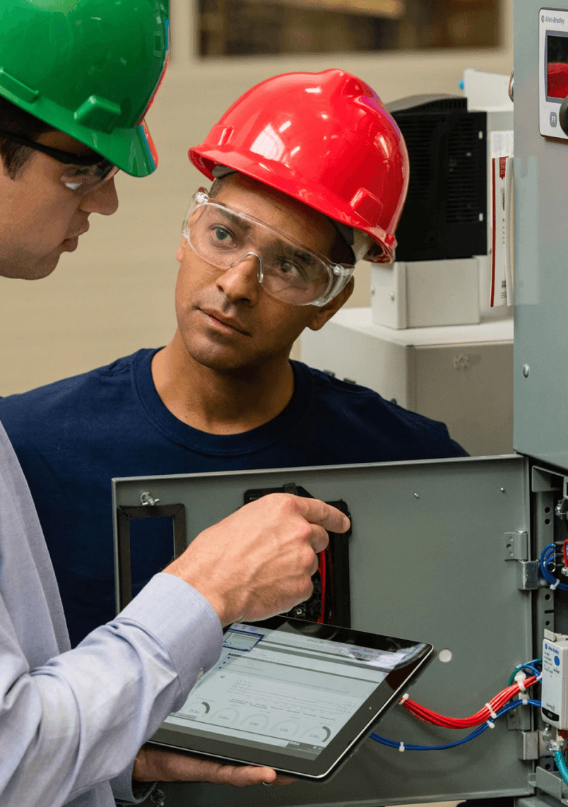 Technician in protective clothing adjusting a pressure gauge on stainless steel industrial machinery